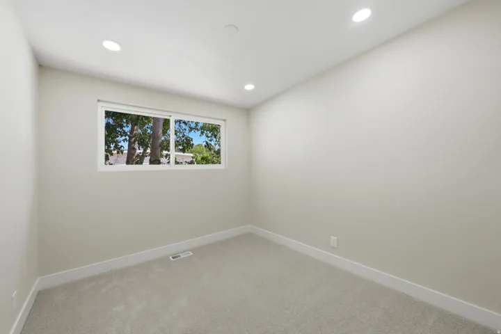 Room featuring a window with exterior tree scenery, recessed lighting, neutral-toned walls, plush carpeting, and white baseboards