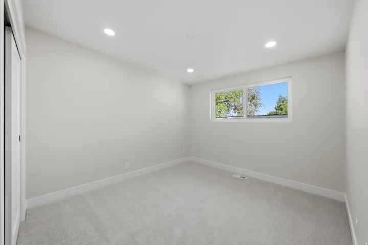 Neutral-toned room featuring a large window, recessed lighting, light gray carpeting, and white baseboards