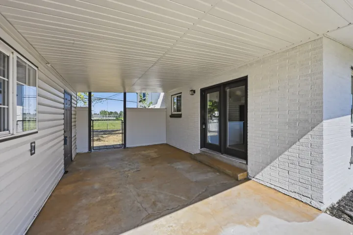 Covered patio featuring a concrete floor, painted brick exterior, and vinyl siding