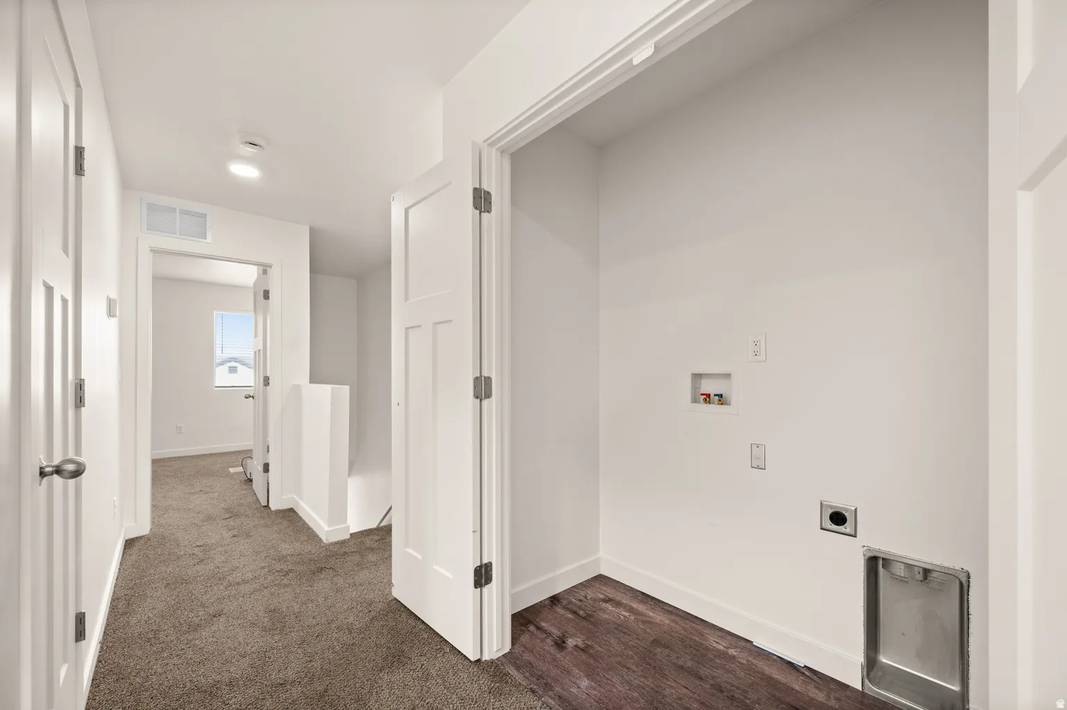Dedicated laundry area with utility hookups and a stainless steel drain pan