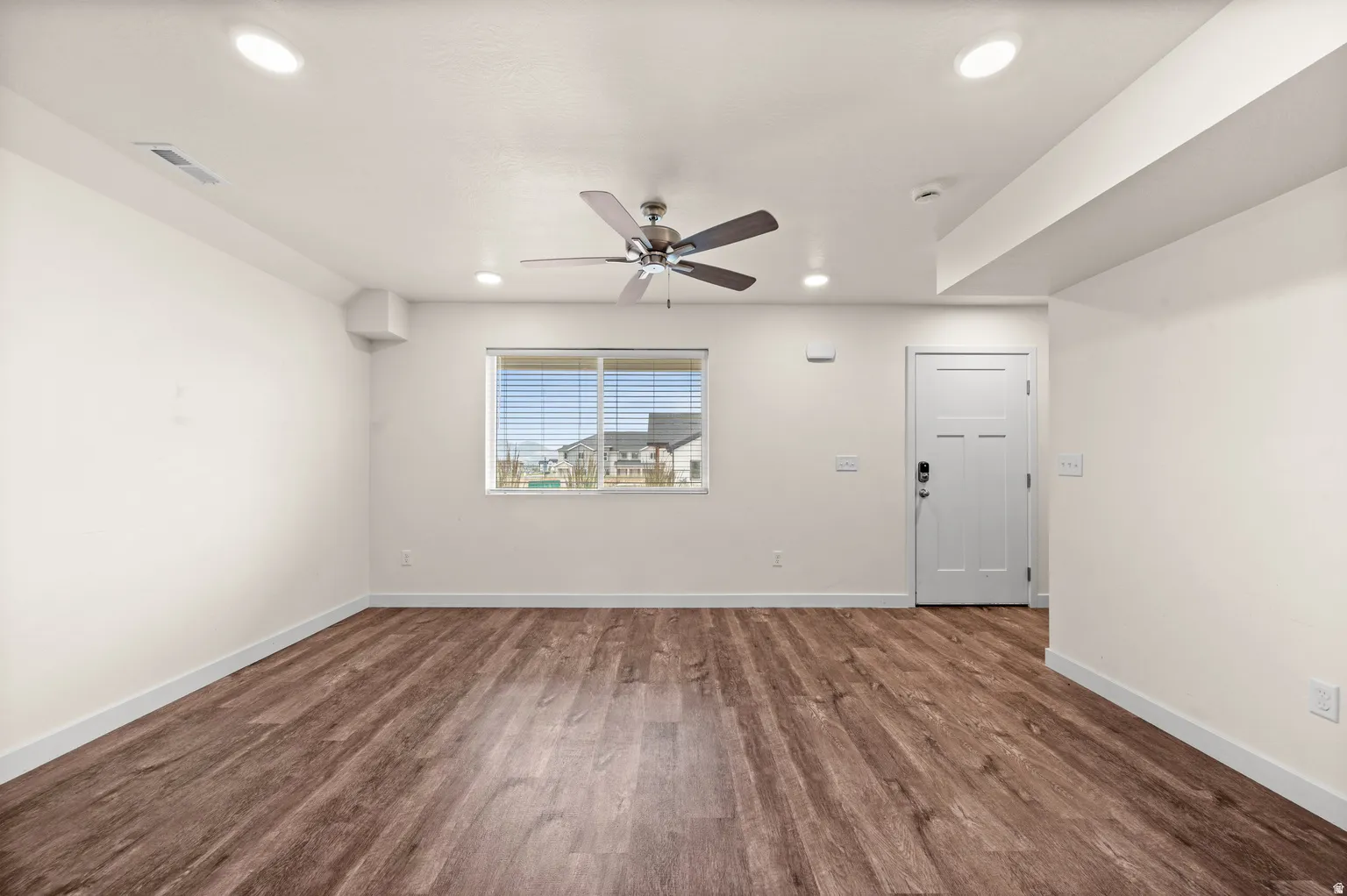 Spacious room featuring wood-finish flooring, recessed lighting, and a ceiling fan