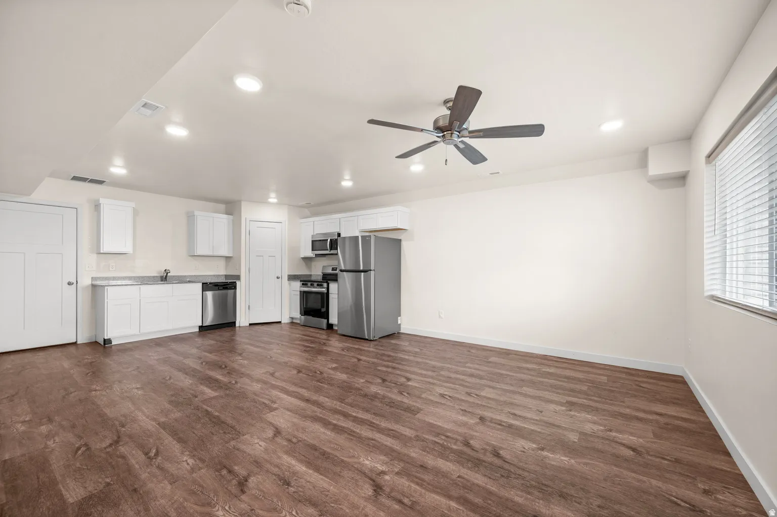 Open-concept living area featuring wood-finish flooring, recessed lighting, and a ceiling fan