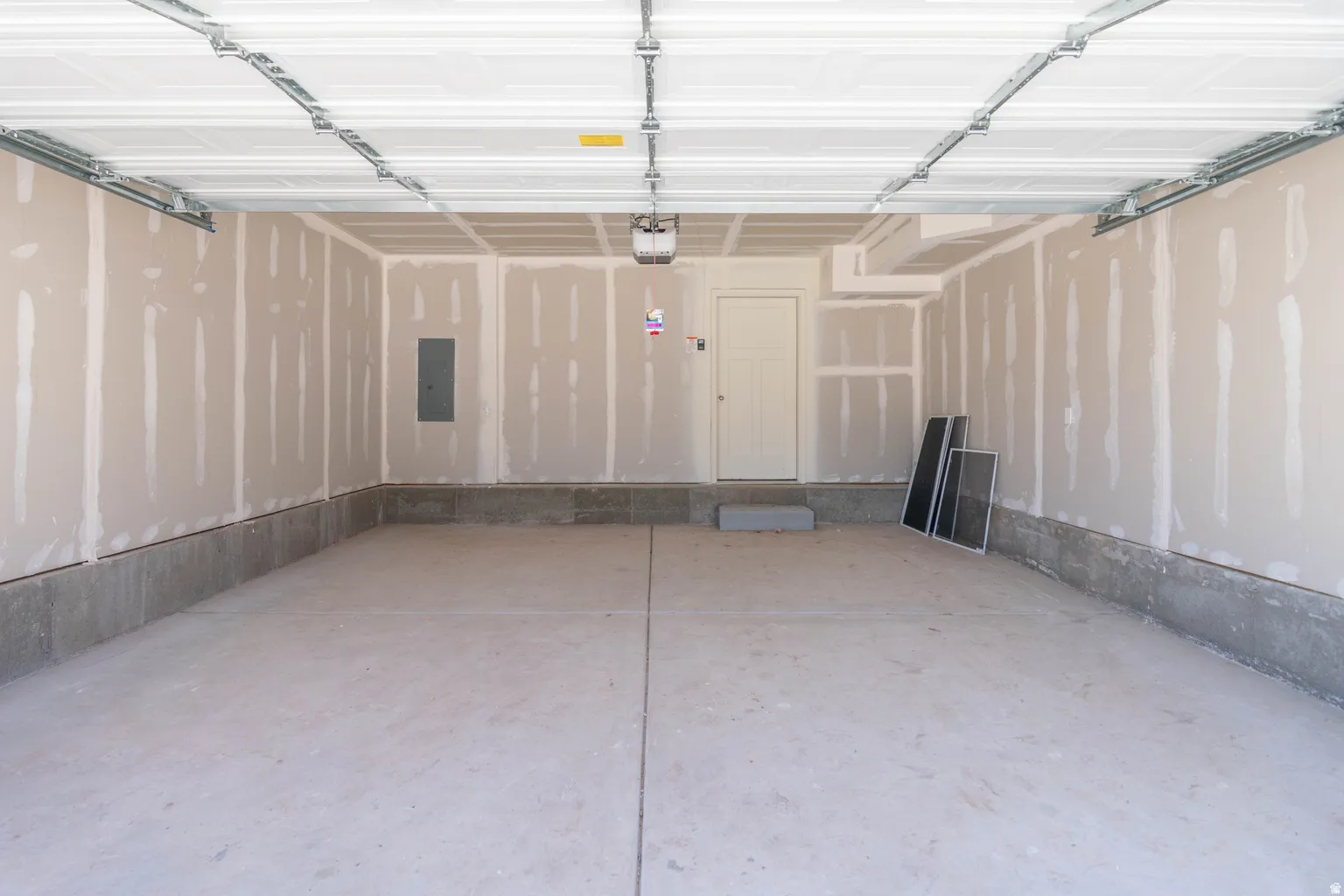 Concrete flooring in a spacious garage with unfinished drywall