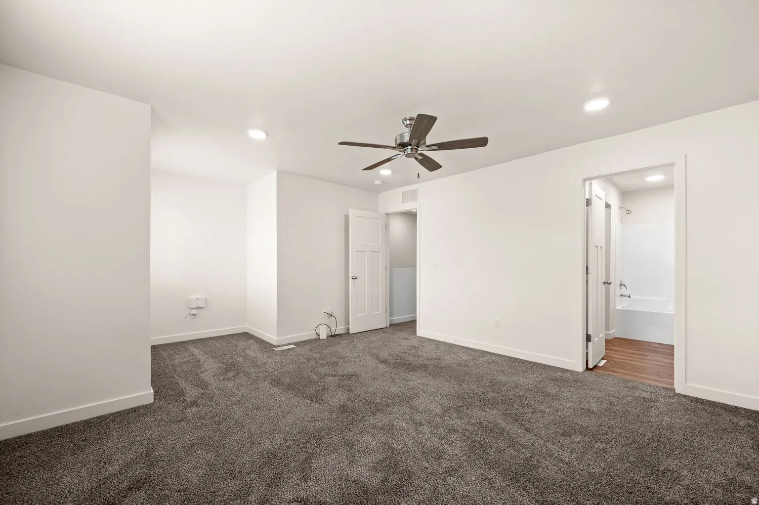 Spacious room featuring plush gray carpeting, recessed lighting, a ceiling fan with integrated lighting, and white trim