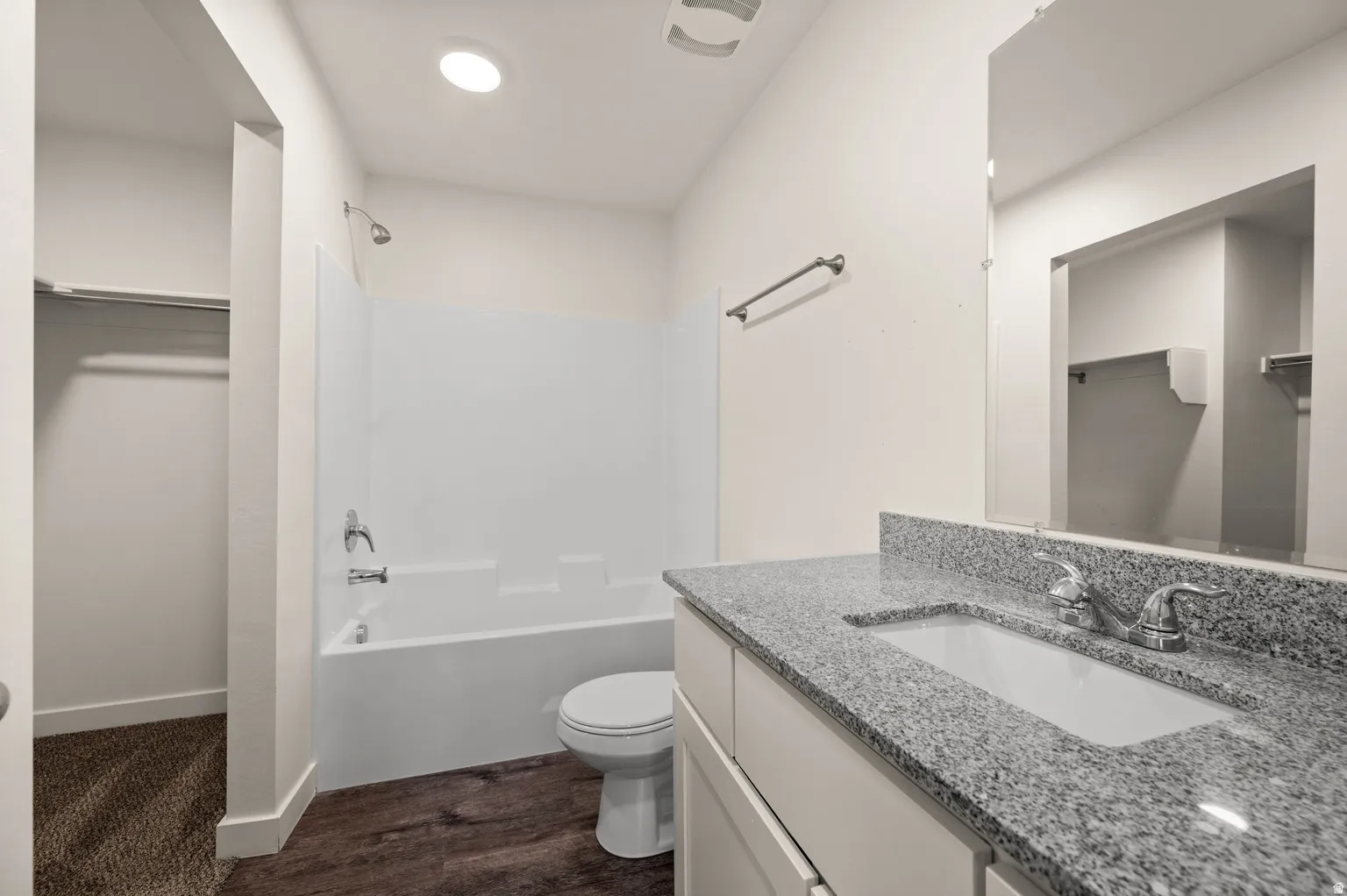 Bathroom featuring a vanity with a light speckled countertop, an undermount sink, and a large wall-mounted mirror