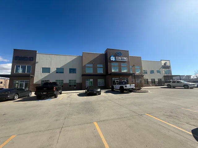 Modern commercial building featuring a multi-textured facade with brick, light-colored siding, and dark accent panels