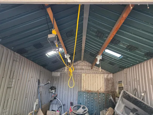 Utility structure with a corrugated metal roof, skylights, and exposed wooden beams