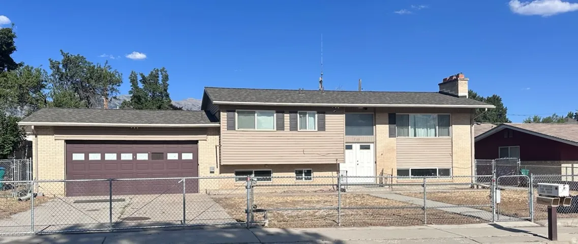 Split-level residence featuring a two-car attached garage with a brown sectional door