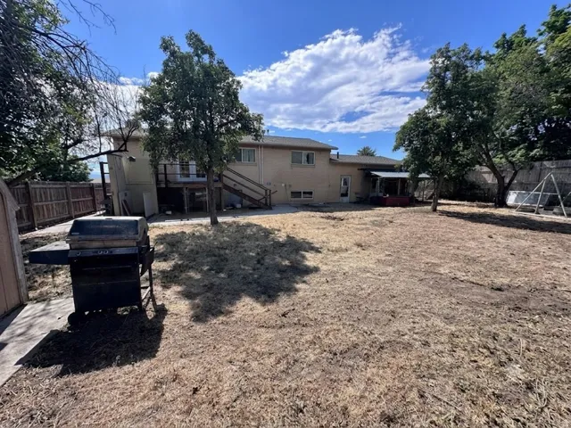 Spacious backyard featuring a multi-level deck, mature trees, and a wooden privacy fence