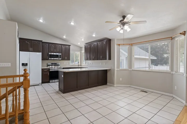 Open-concept kitchen and dining area featuring vaulted ceilings, recessed lighting, and tile flooring