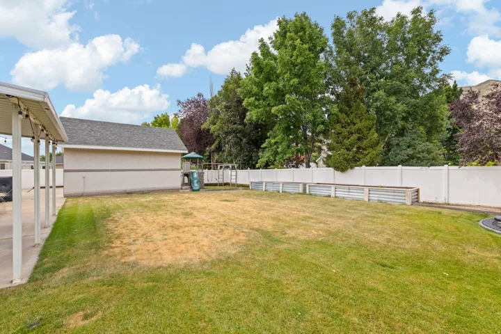 Spacious backyard featuring a covered patio, a detached structure with shingled roofing, and a privacy fence