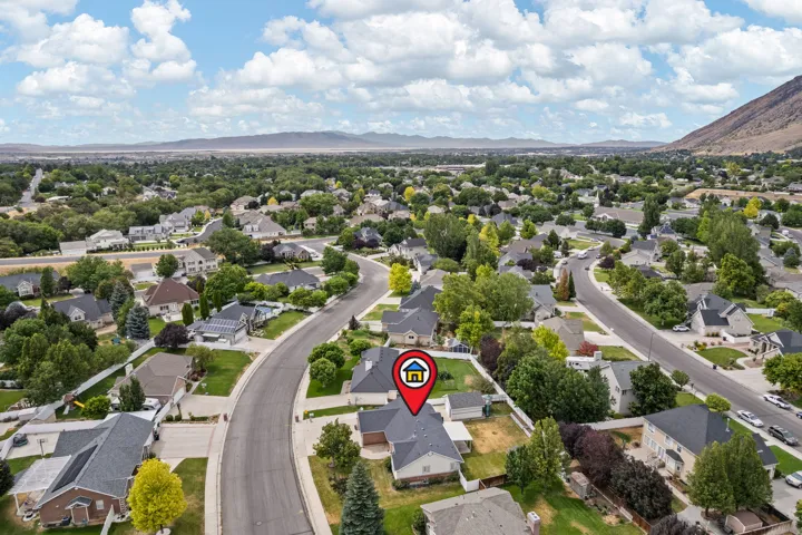 Aerial perspective of a residential neighborhood featuring established homes with dark shingle roofs, mature trees, and curved streets