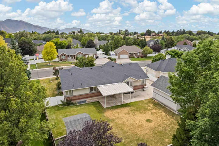 Aerial view of the property featuring a single-story residence with a dark shingle roof and a two-tone exterior of brick and light siding