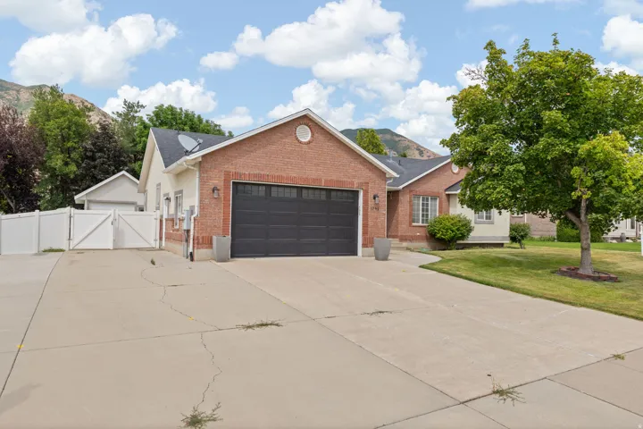 Brick and siding exterior with an attached garage, paved driveway, and side yard access