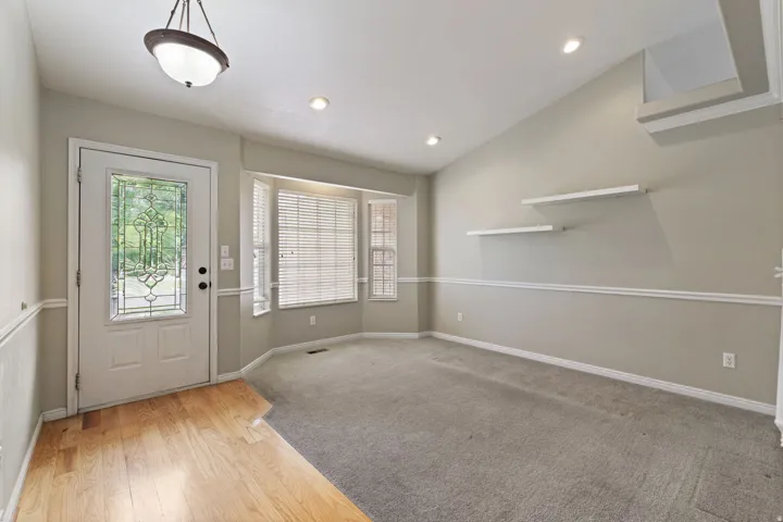 Entryway featuring a decorative glass panel door, wood-finish flooring, and a bay window
