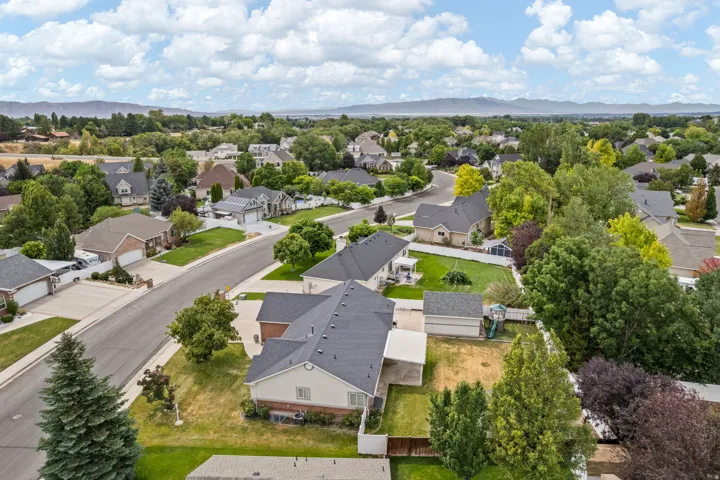 Aerial overview of a residential neighborhood with a variety of single-family homes, mature landscaping, and mountain ranges in the distance