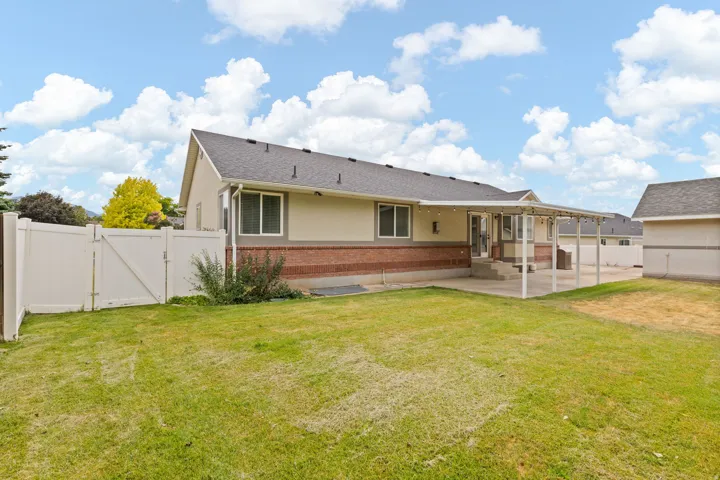 Expansive backyard featuring a covered patio, concrete surface, and white privacy fencing