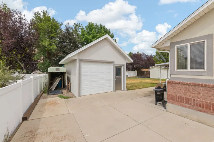 Detached single-car garage featuring a white panel door and an adjacent side door