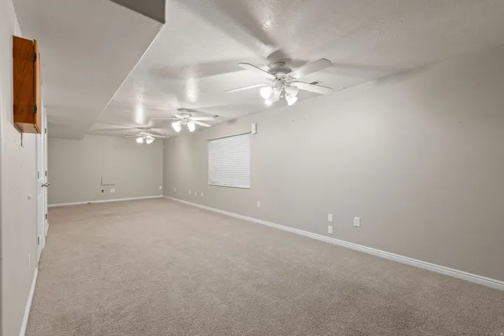 Spacious room with neutral-toned carpet flooring and light gray walls