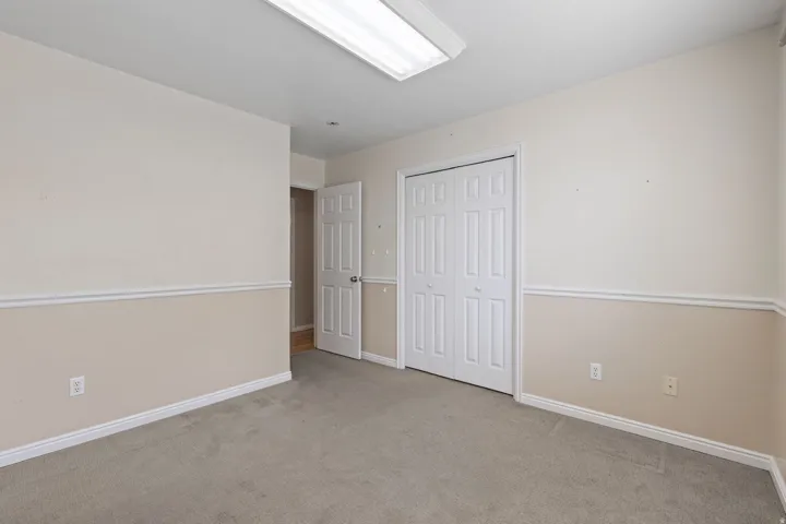 Carpeted room featuring bi-fold closet doors, a paneled interior door, and two-tone wall finishes with chair rail molding