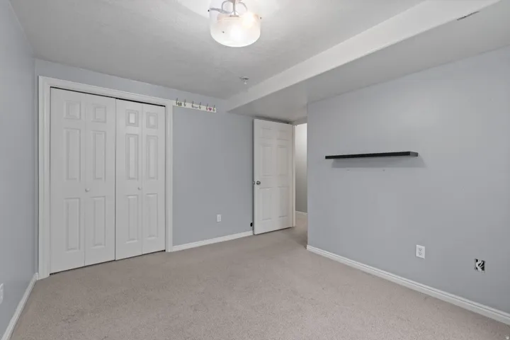 Carpeted room featuring a double bifold closet, light gray wall paint, and a semi-flush mount ceiling light fixture