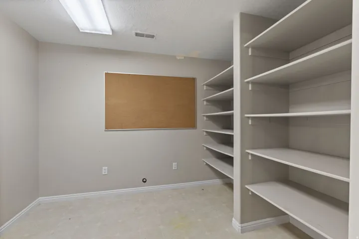 Room featuring extensive built-in shelving, light-toned walls, and a recessed fluorescent light fixture