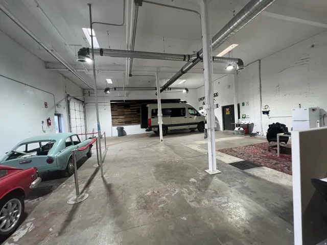 Spacious open-concept commercial interior featuring exposed ductwork, concrete flooring, and multiple ceiling-mounted light fixtures