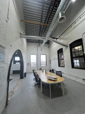 Spacious interior featuring exposed spiral ductwork and white-painted brick walls