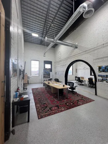 Spacious interior featuring exposed industrial-style ductwork and a high, sloped ceiling