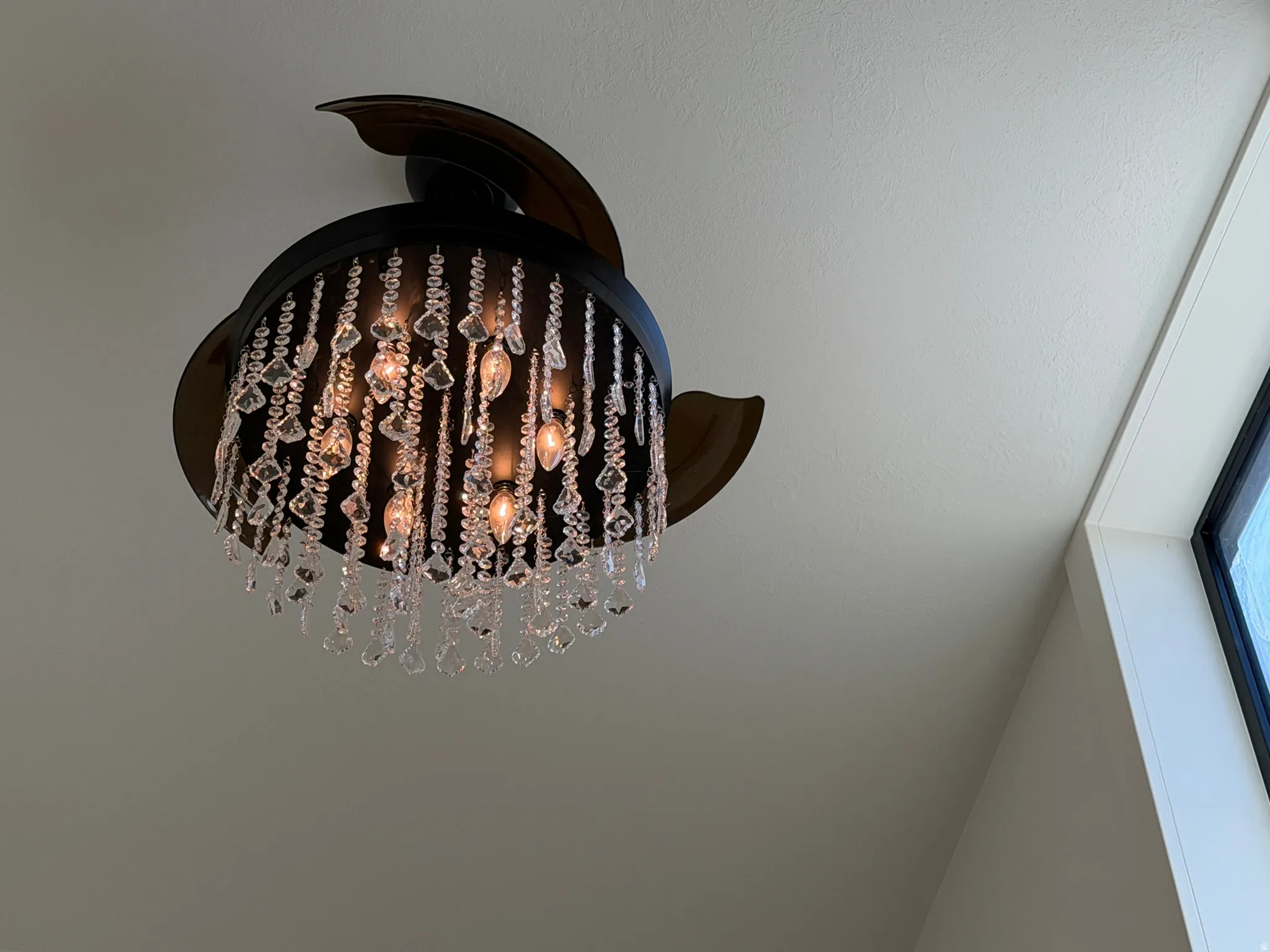Ceiling fan with ornate crystal chandelier light kit, featuring bronze-finish fan blades and multiple light bulbs