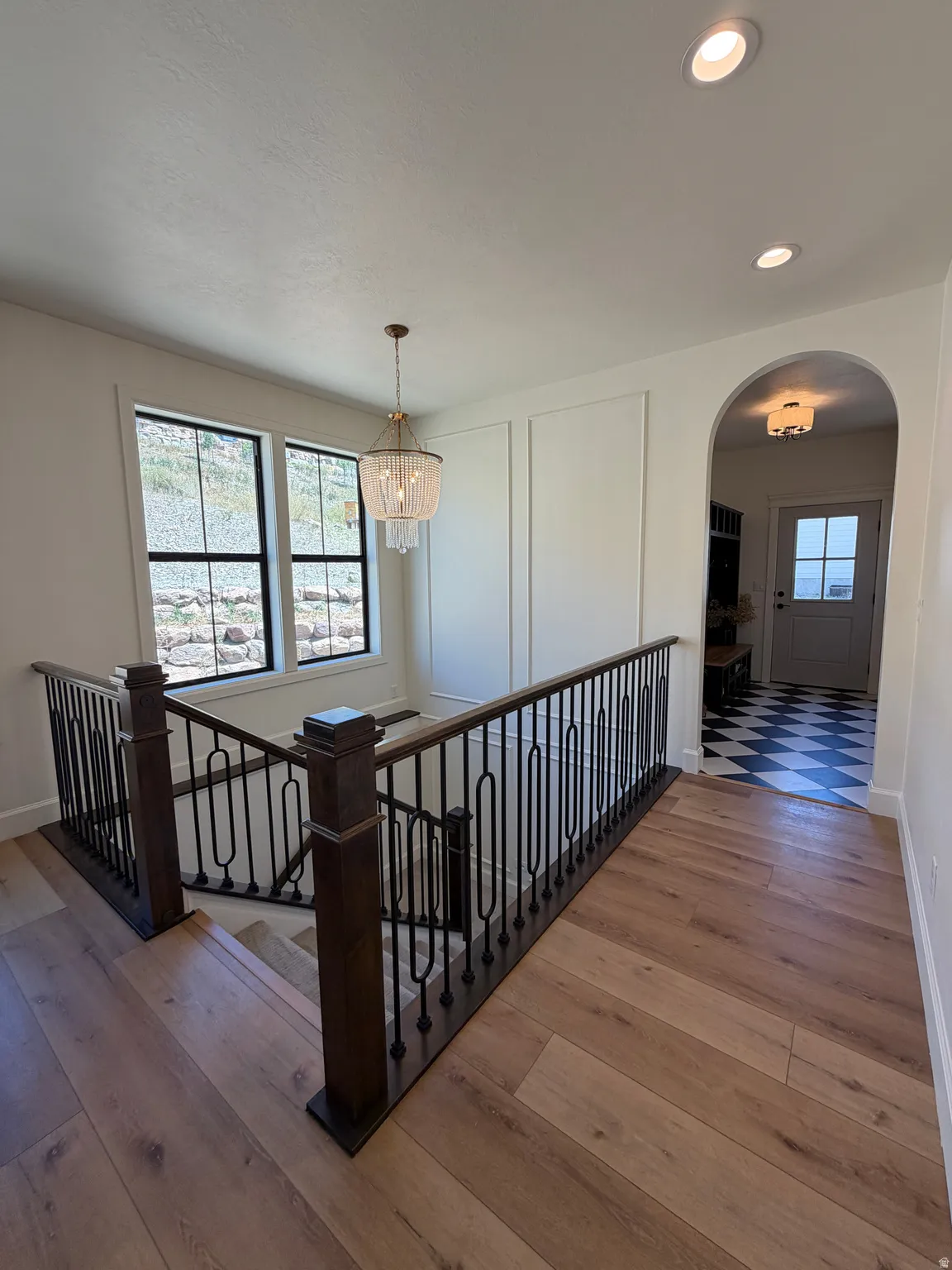 Upper landing featuring wood-finish flooring, a decorative chandelier, recessed lighting, and a dark wood and wrought iron staircase railing