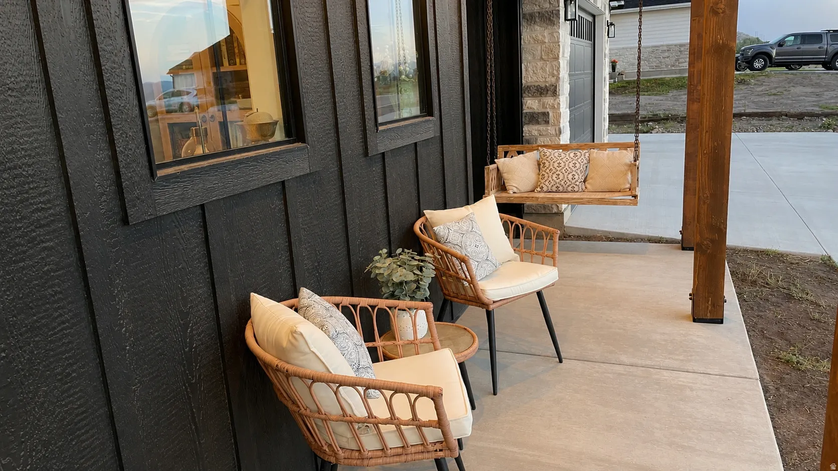 Covered porch featuring a concrete surface, black vertical siding, and a wooden support column