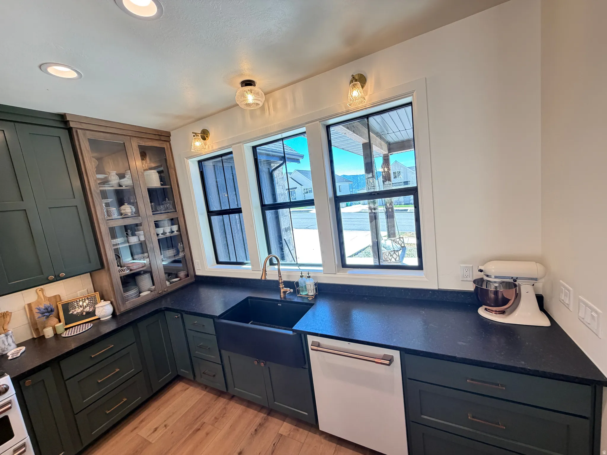 Kitchen featuring dark green cabinetry, black farmhouse sink, and black countertops
