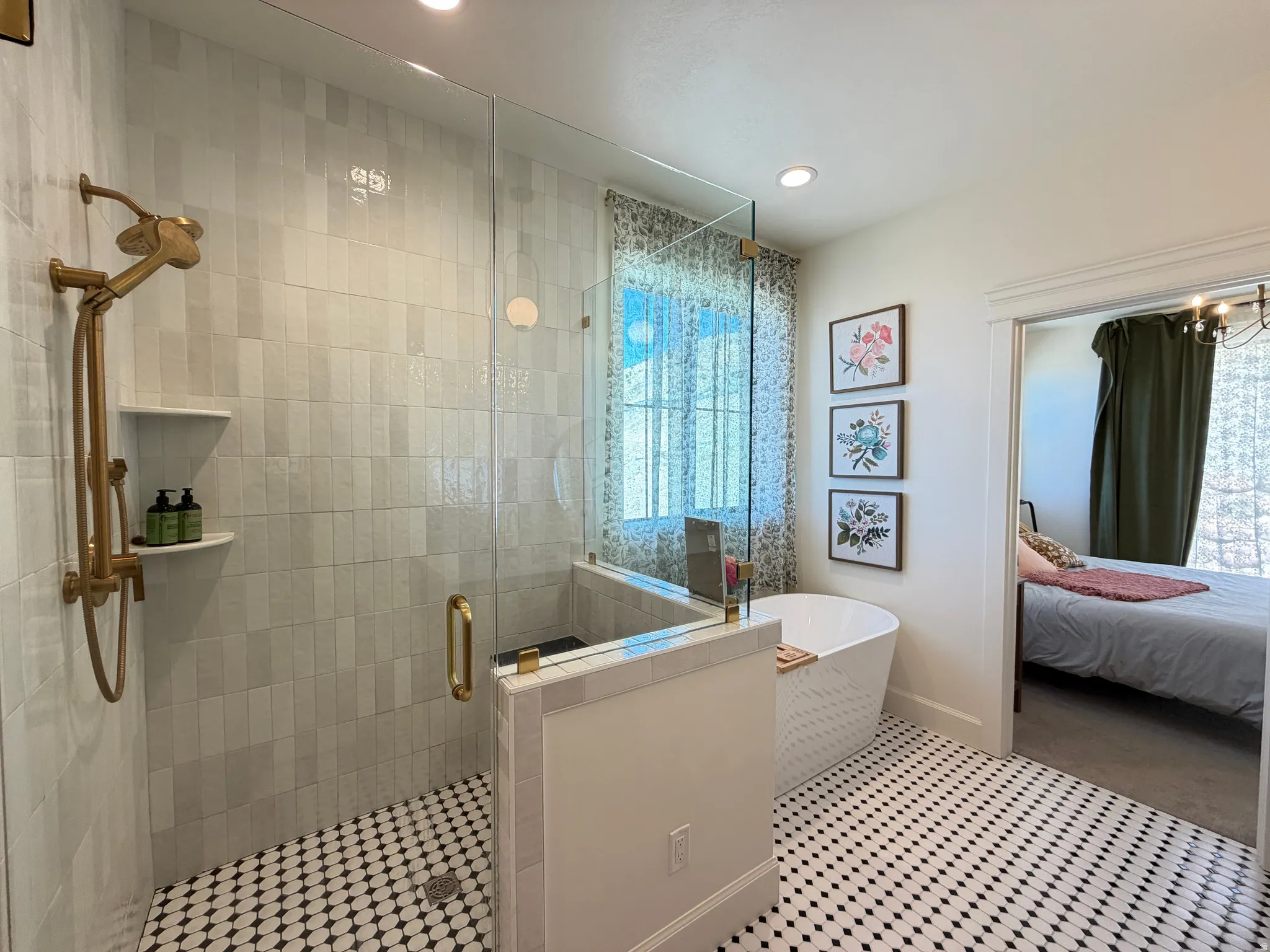Primary bathroom featuring a freestanding soaking tub, a walk-in shower with clear glass enclosure and gold-finish fixtures, and distinctive black and white patterned floor tiling and walking closet