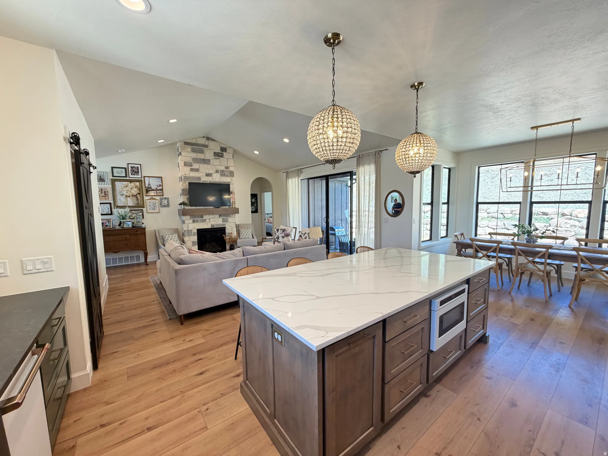Spacious interior featuring wood-finish flooring, a kitchen island with a light-toned Quartz countertop w/ a microwave drawer and lots of storage.