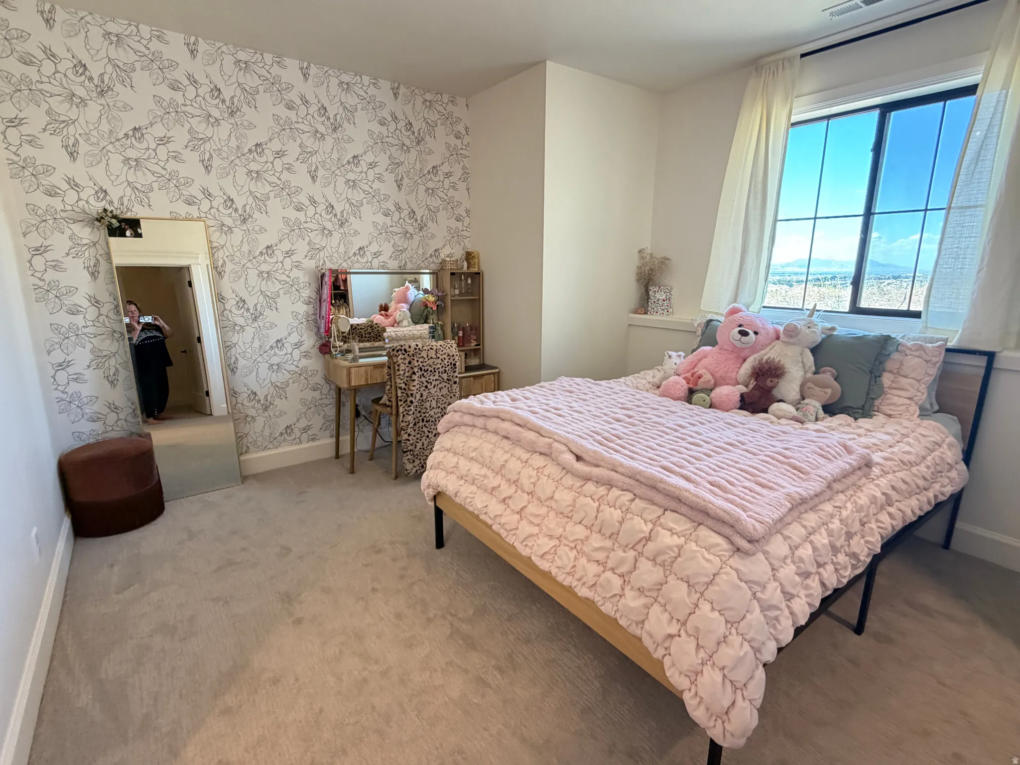 Bedroom 3 in the bsmnt that has a bathroom attached.  Spacious room featuring a large window, patterned accent wall, light-colored carpeting, and white baseboards