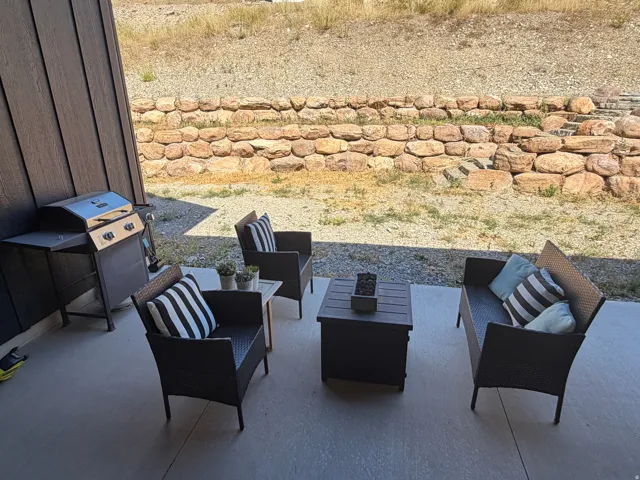 Outdoor patio featuring a concrete surface, dark horizontal siding, and a stone retaining wall