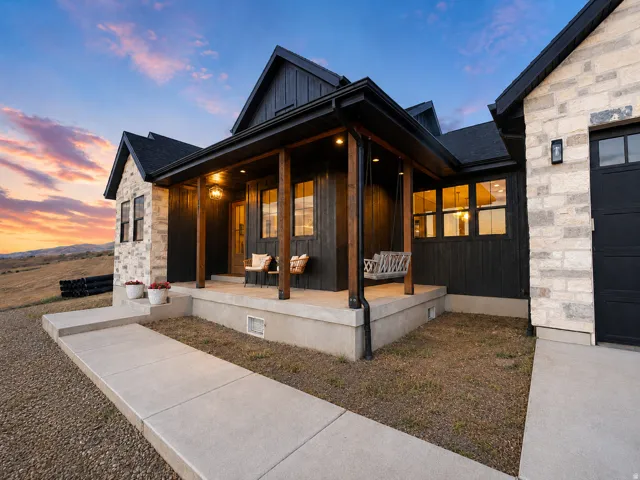 Modern farmhouse exterior featuring black vertical siding and light-toned stone accents