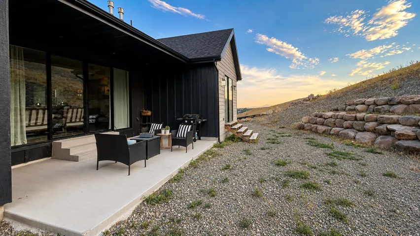 Exterior patio featuring a concrete surface, black siding, and expansive glass sliding doors