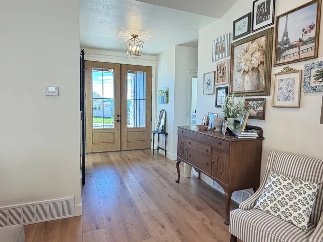 Entryway featuring light wood-finish flooring, a brass-toned foyer light fixture, and double entry doors with integrated window panes