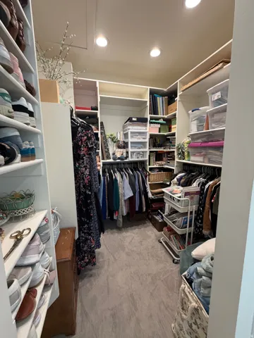 Walk-in closet featuring extensive built-in shelving, multiple hanging rods, recessed lighting, and carpet flooring