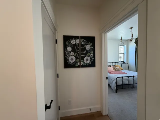 Hallway featuring white trim and solid core door with matte black hardware, opening to the Primary Bedroom Suite.