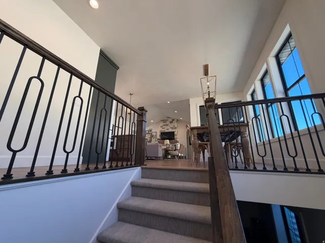 Carpeted staircase with dark wood handrail and decorative metal balusters