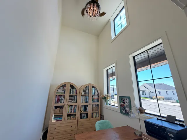 Vaulted ceiling featuring a decorative chandelier and multiple windows