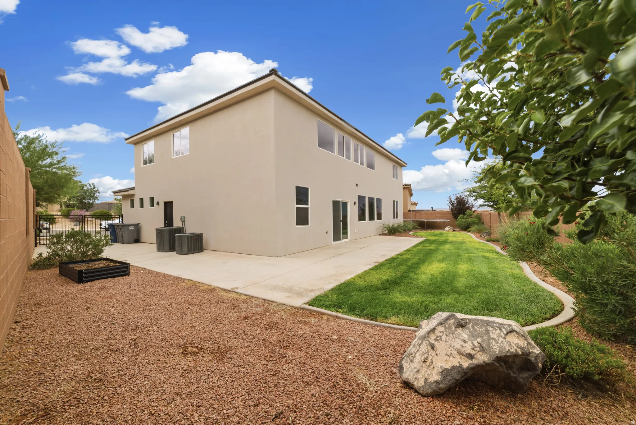 Expansive backyard featuring a manicured lawn, concrete patio, and gravel landscaping