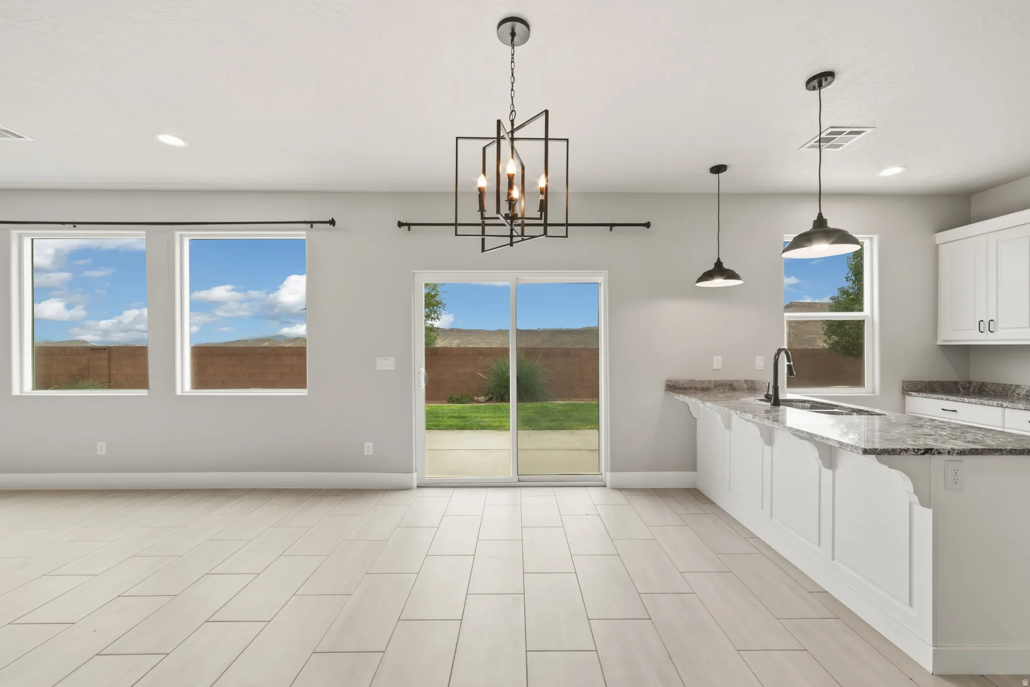 Open-concept living area featuring light wood-finish plank flooring, recessed lighting, and a modern geometric chandelier