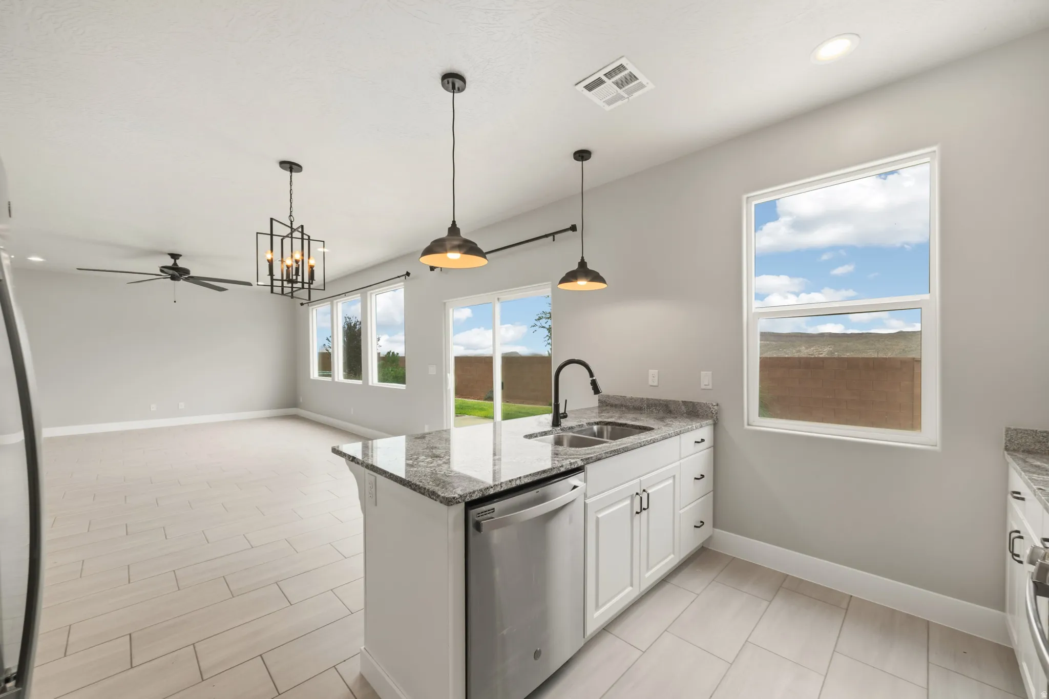 Kitchen island with granite countertop, stainless steel sink, and pendant lighting