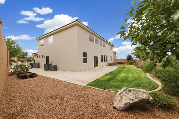 Expansive backyard featuring a manicured lawn, concrete patio, and gravel landscaping