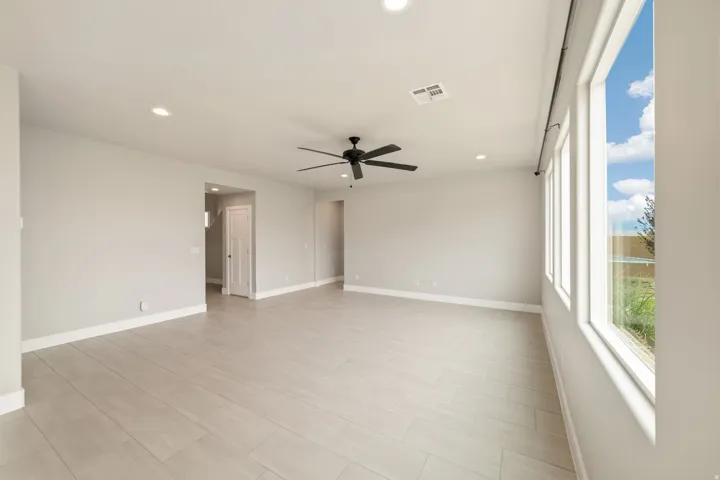 Spacious room featuring light-toned tile flooring, recessed lighting, and a ceiling fan