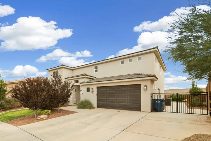 Contemporary two-story home showcasing a modern stucco exterior with clean architectural lines, a spacious concrete driveway, and a three-car garage with dark panel doors